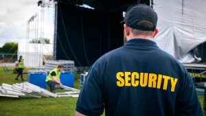 Rear View Of Security Team At Outdoor Stage For Music Festival Or Concert